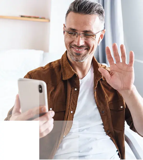 image of a man smiling & waving to someone while on a video call